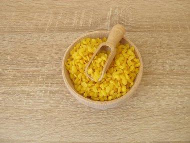 Doğal kozmetik, mum veya arı sargıları için ahşap bir kapta saf balmumu pastilles