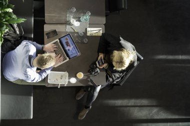 Kafedeki teknolojiyi kullanan çiftlerin üst görünümü