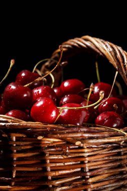 Siyah bir zemin üzerine bir hasır sepet içinde olgunlaşmış kiraz