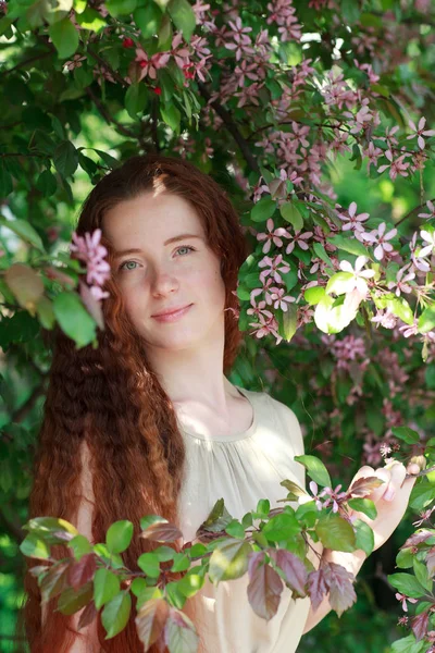 Vacker Kvinna Med Långa Röda Hår Nära Ett Blommande Träd — Stockfoto