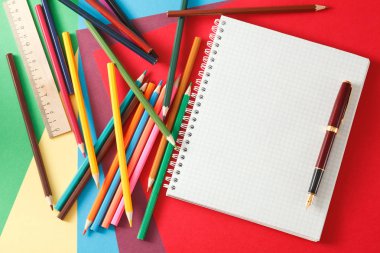 Defter, kırmızı kalem ve kurşun kalem renkli kağıda yalan. 