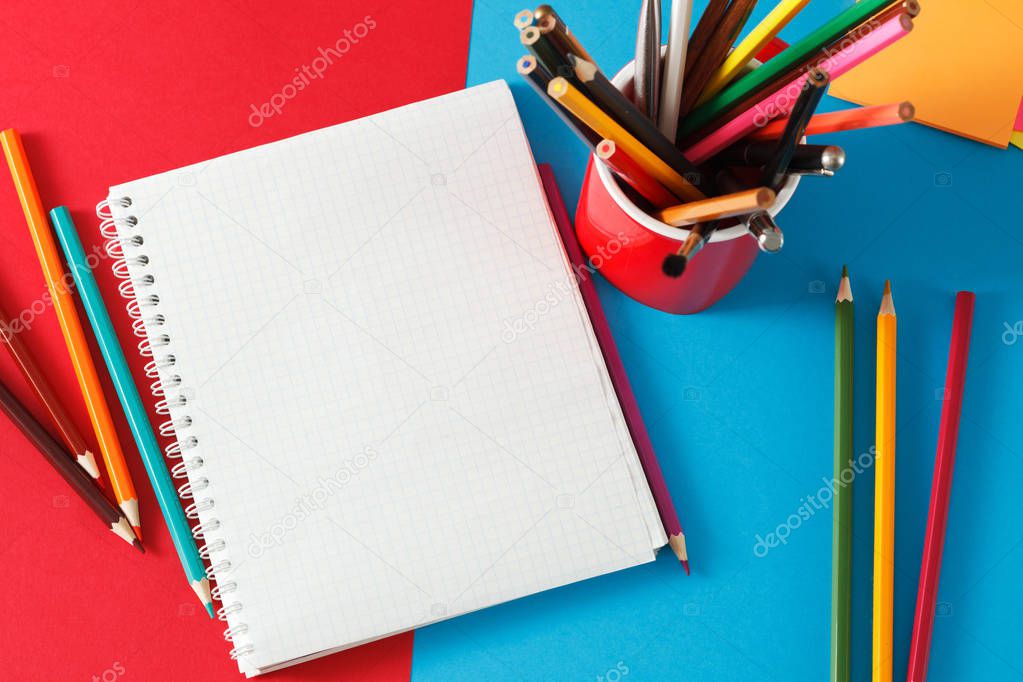 Notebook and pencils lie on colored paper. 