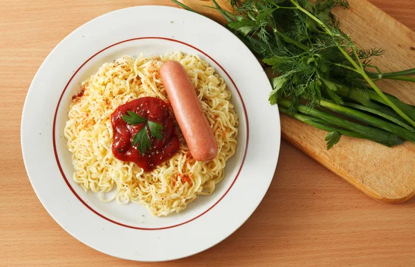 Noodles with sausage and red ketchup in a plate