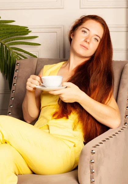Красивая Женщина Жёлтом Костюме Чашкой Сидящей Кресле — стоковое фото