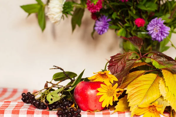 Autumn composition of apples and flowers on the table