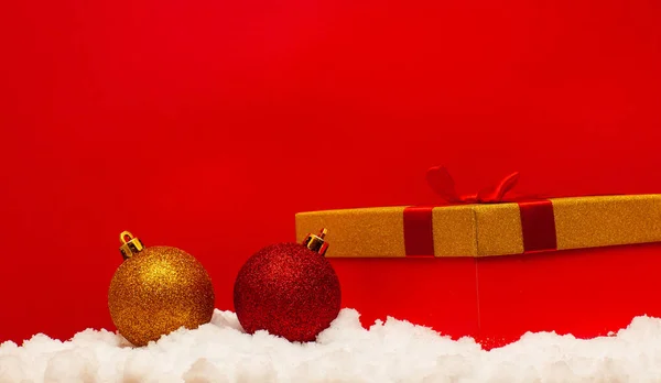 Geschenk Und Weihnachtskugel Auf Schnee Auf Rotem Hintergrund — Stockfoto