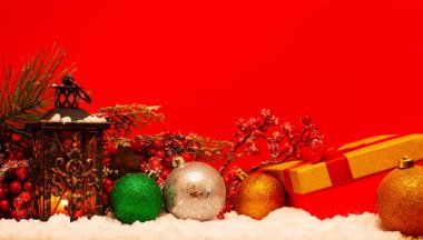 Fener, hediye ve Noel topları üstünde kar kırmızı zemin üzerine mum