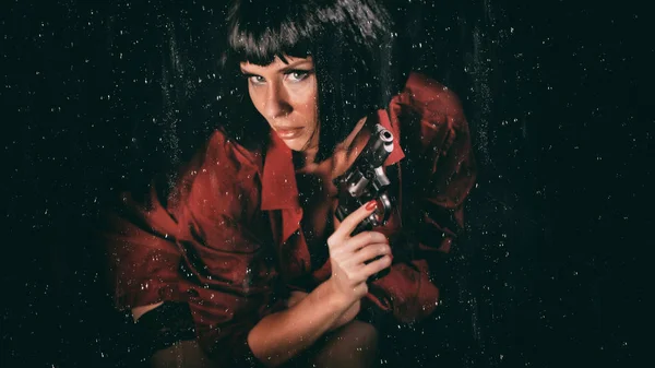 stock image Beautiful woman with a revolver in her hands and raindrops flowing down the glass on black