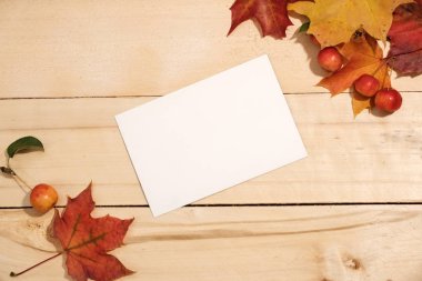akçaağaç yaprakları ve ahşap bir masa üzerinde bir fotoğraf kartı