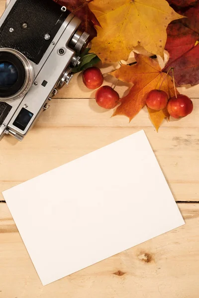 Vecchia macchina fotografica, foglie d'acero e una carta fotografica su un tavolo — Foto Stock