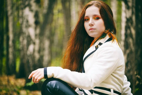 Woman with long hair and bright makeup in the autumn park — Stock Photo, Image