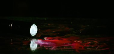 Siyah arka planda kan gölündeki el feneri.