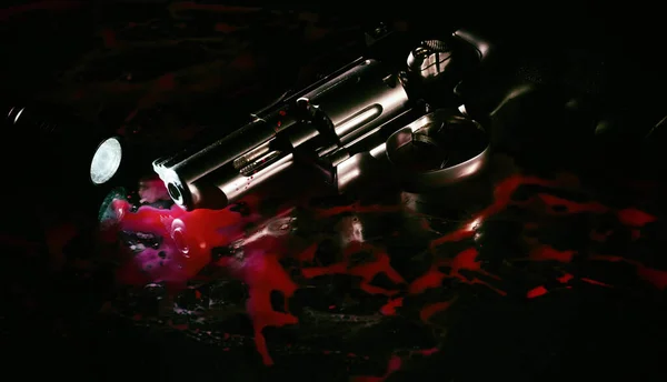 黑色背景的血泊中的左轮手枪和手电筒 — 图库照片