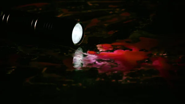 Taschenlampe Einer Blutlache Auf Schwarzem Hintergrund — Stockfoto