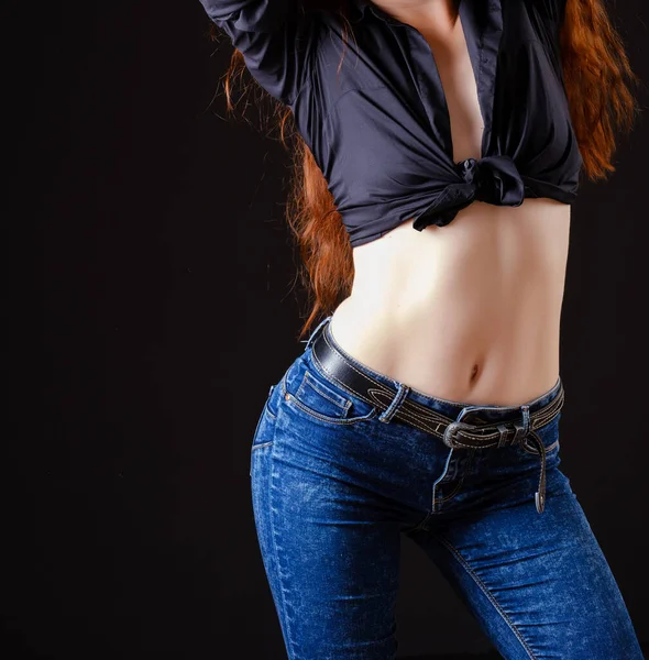ジーンズに長い赤い髪をした美しい若い女性黒の上に裸の腹 — ストック写真