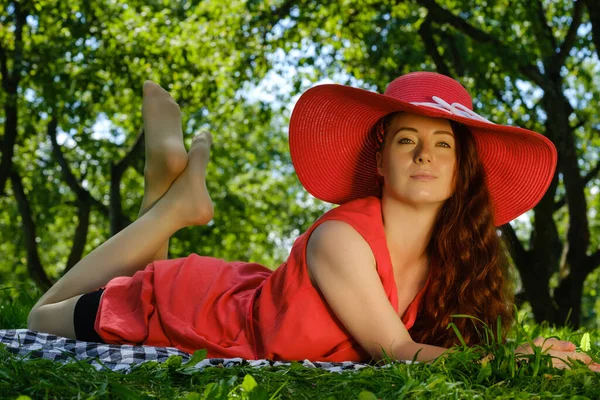 Beautiful Young Woman Red Dress Hat Lies Park Summer — Stock Photo, Image