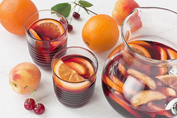 白い木製の背景にピーチとオレンジ フルーツ グラス赤ワインのサングリア夏ドリンク — ストック写真