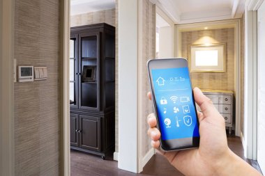 Ev aletleri kontrol etmek için cep telefonu kullanan kişi.