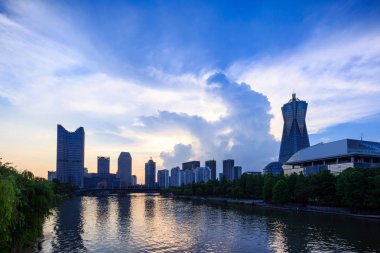 alacakaranlıkta bir nehir boyunca modern bir şehir gökdelenler