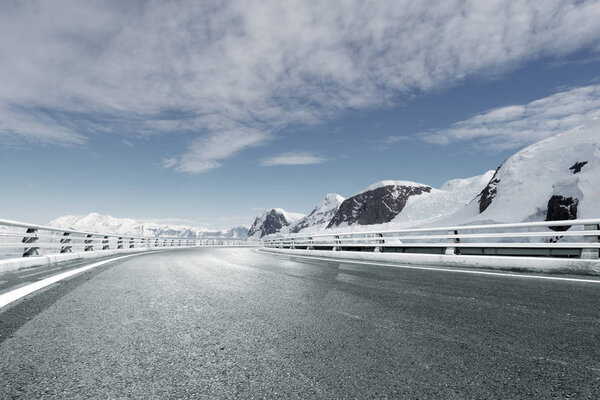 empty asphalt road with snow mountains