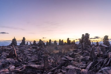 Tibet'te gündoğumu ile dağın zirvesinde denge taş yığını