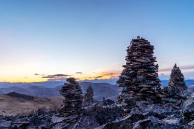 Tibet'te gündoğumu ile dağın zirvesinde denge taş yığını