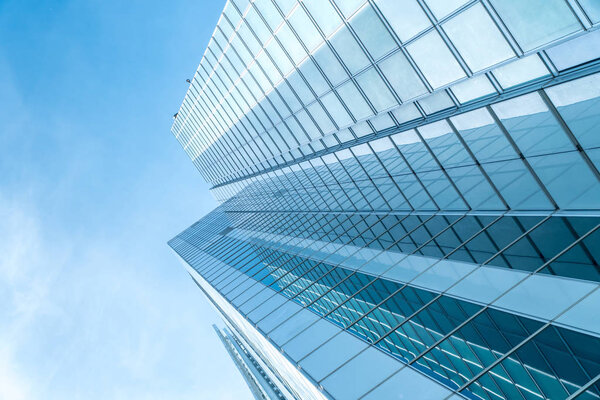 Low angle view of a blue skyscraper on a blue cloudscape background