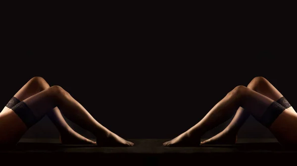 黒い背景の前に黒いストッキングの2人の女性の足 — ストック写真