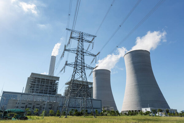 thermal power plant and high voltage transmission pylon against a blue sky