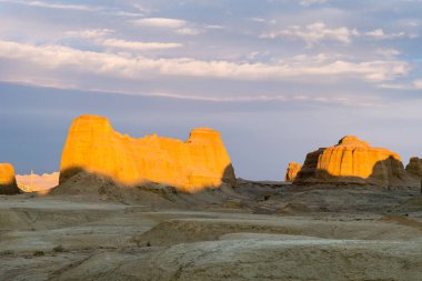 xinjiang wind erosion landform landscape in sunset, urho ghost town, China clipart