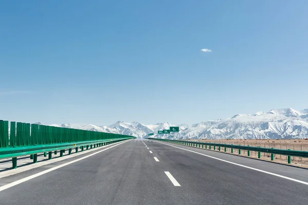 Highway with snow mountains — Stock Photo, Image