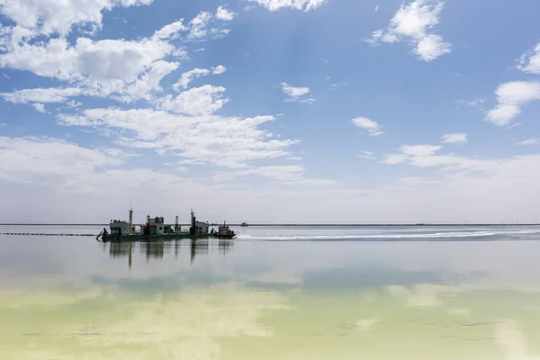 Só bányászati hajó és a kék ég elmélkedés a qarhan Salt Lake — Stock Fotó