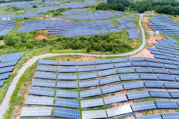 Tepenin yamacında güneş enerjisi, fotovoltaik panellerin hava görüntüsü