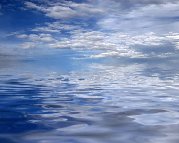 reflection of a blue cloudy sky in the ocean surface