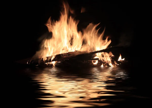 bright fire of burning shipwreck debris on the surface of the water