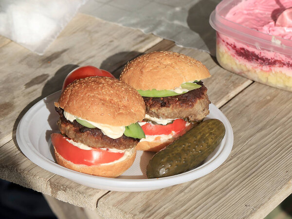 котлета со свежими помидорами и огурцами в булочке, лежащей на деревенском столе, сэндвич
