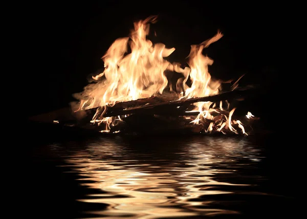在水面上漂浮的运输废墟上的明亮的火 — 图库照片