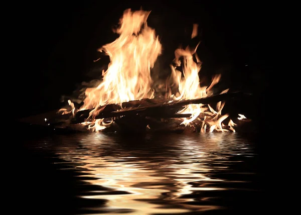 在水面上漂浮的运输废墟上的明亮的火 — 图库照片