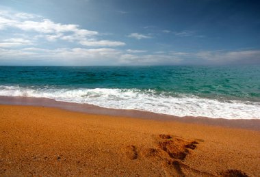 seyahat için bir yer olarak bulutlu güneşli gökyüzü altında kumlu plaj