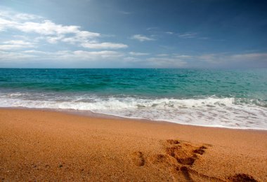 seyahat için bir yer olarak bulutlu güneşli gökyüzü altında kumlu plaj