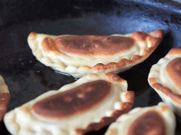 cooking fried pies in hot oil in a pan