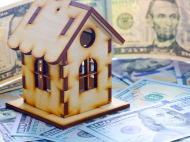 ahşap ev kağıt faturaları dolar yığını üzerinde ipotek bir sembolü olarak duruyor.