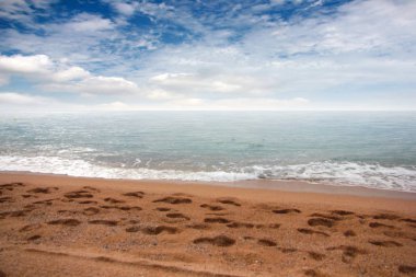 kumlu plaj ve bulutlu gökyüzü ufukta