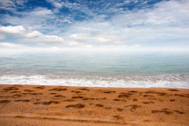 kumlu plaj ve bulutlu gökyüzü ufukta