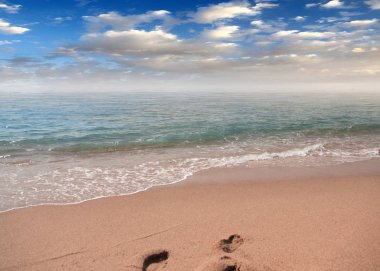 kumlu plaj ve bulutlu gökyüzü ufukta