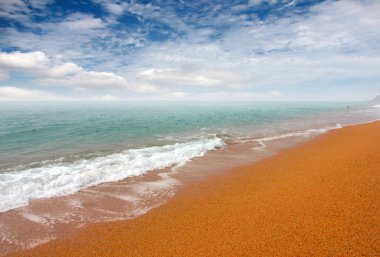 kumlu plaj ve bulutlu gökyüzü ufukta