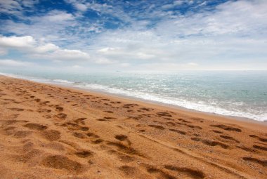 kumlu plaj ve bulutlu gökyüzü ufukta