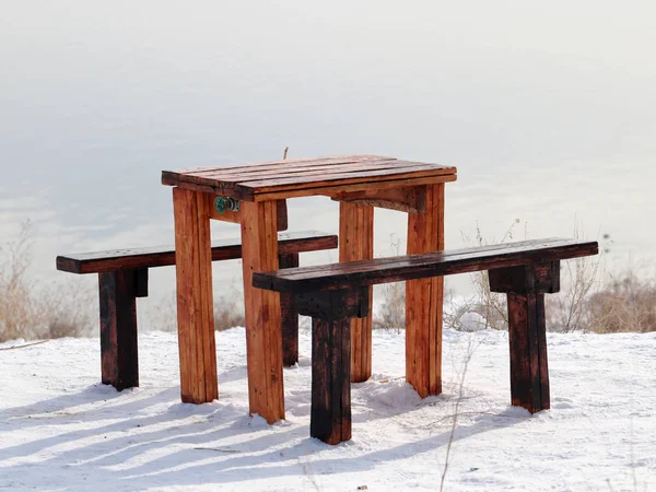 wooden table and bench on the snowy ground as a resting place