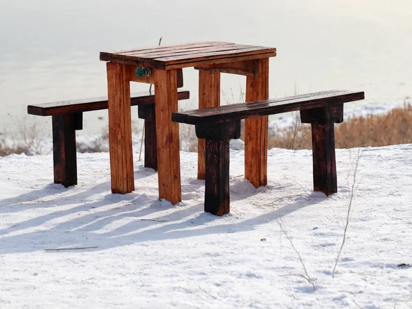 wooden table and bench on the snowy ground as a resting place