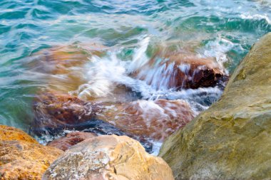 dalgalar ve fışkıran deniz su akan büyük taşların üzerinde